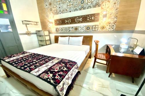 a bedroom with a bed and a desk with a bedspread at OYO Homes 93608 YY's House Syariah in Klaten