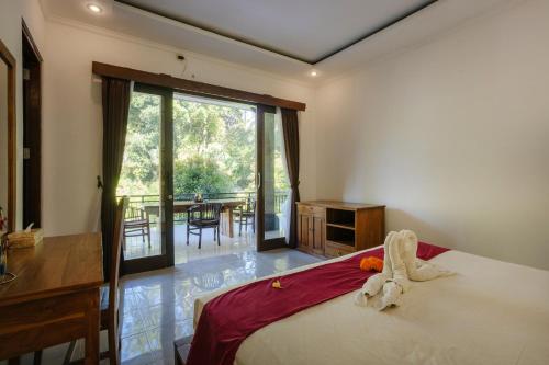 a bedroom with a bed and a balcony with a table at Ubud Harmony Private Villa and Pool in Ubud