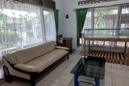 a living room with a couch and some windows at SPOT ON 93606 Juan Kostel 3 in Purwokerto