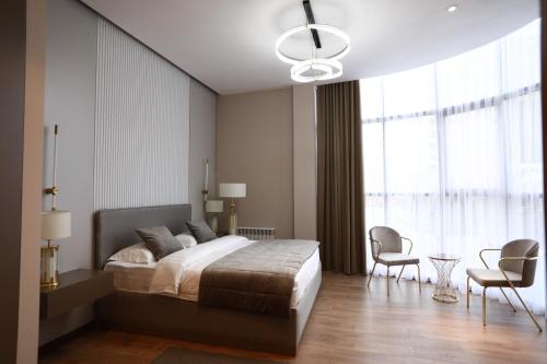 a bedroom with a bed and chairs and a large window at IsraHotel Dushanbe in Dushanbe