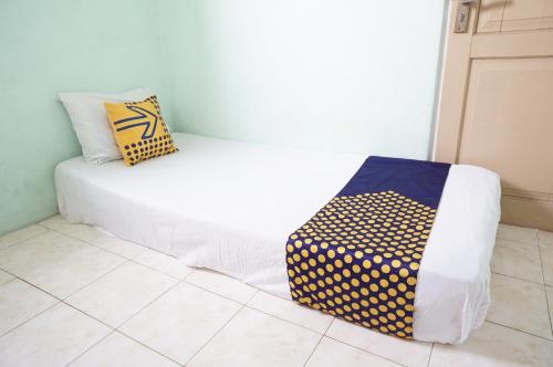 uma cama branca com duas almofadas no topo de um piso em SPOT ON 93611 Kost Pak Suyatno Syariah 2 em Ponorogo