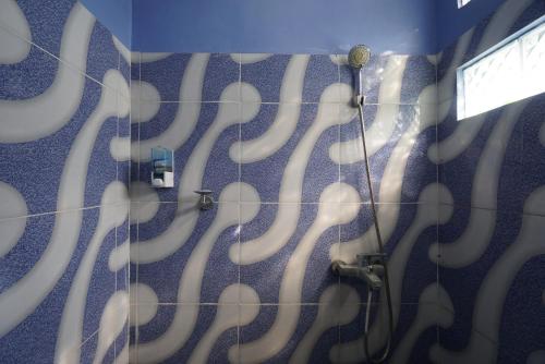 uma casa de banho com um chuveiro com redemoinhos brancos na parede em SPOT ON 93620 Anisa Homestay Syariah em Tulungagung