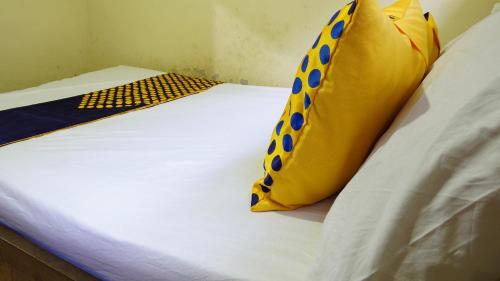ein Bett mit einem gelben und blauen Kissen darauf in der Unterkunft SPOT ON 93621 Kost Bu Tutik Syariah in Lawang
