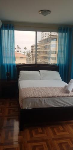 a bedroom with a bed and a large window at Hostal Costa Linda Salinas in Salinas