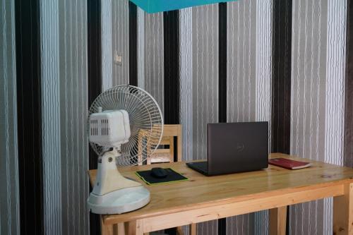 einen Schreibtisch mit einem Ventilator und einem Laptop in der Unterkunft SPOT ON 93622 Wisma Dua Putra Syariah in Majalengka