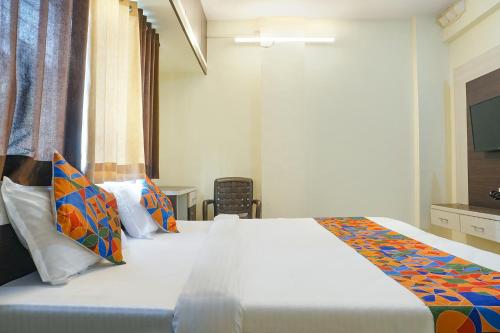 a bedroom with a large white bed with colorful pillows at FabExpress The Guest House in Pune