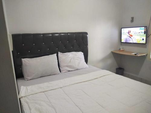 a bedroom with a bed with a black headboard and a television at OYO 93630 Wongso Residence Syariah in Pangkalpinang