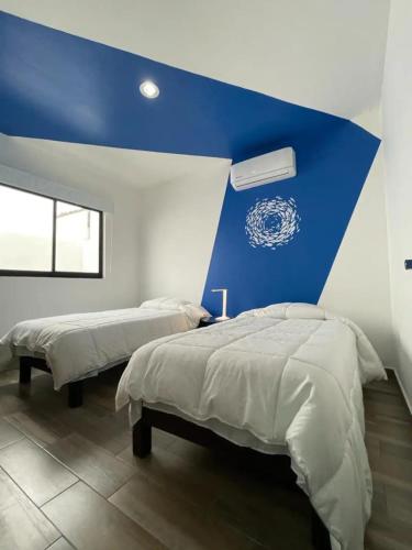 a bedroom with two beds and a blue wall at La casa del faro Azul Marino in Mazatlán