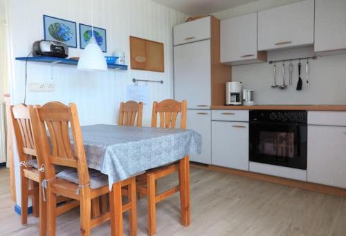 une cuisine avec une table et des chaises et une cuisine avec des placards blancs dans l'établissement Möve Aba Bungalow 66, à Rerik