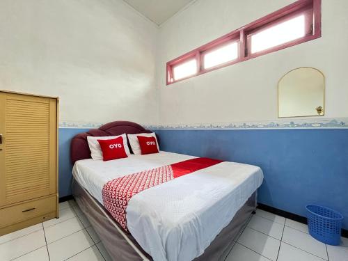 a bedroom with a bed with red pillows on it at OYO 93629 Villa Cemara Syariah in Mojokerto