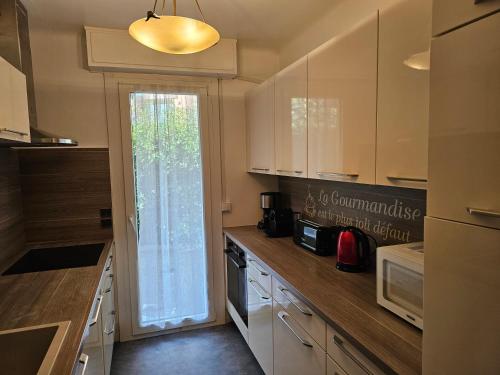 une cuisine avec des armoires blanches et une fenêtre dans l'établissement Duplex climatisé 100m2, jardin, garage individuel clos, à Antibes