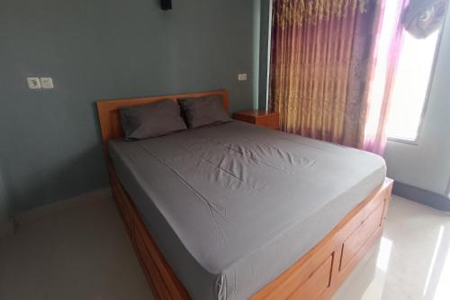 een slaapkamer met een bed met een houten frame en een raam bij OYO 93638 Lotus Guest House in Lombok