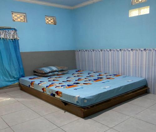 Bett in einem Schlafzimmer mit blauer Wand in der Unterkunft SPOT ON 93639 Kaila Guesthouse in Lombok