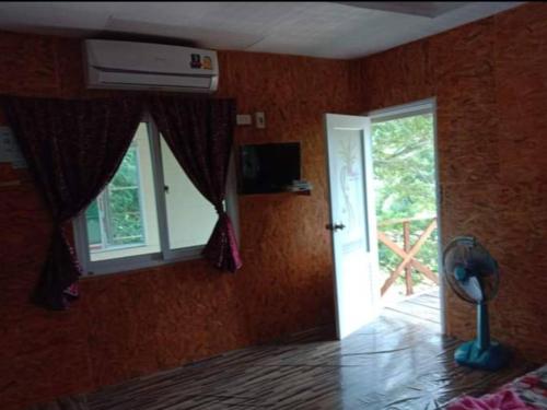 a room with a bedroom with a window and a fan at Ameen Homestay อามีน โฮมสเตย์ in Ban Komo Sam Sip Paet