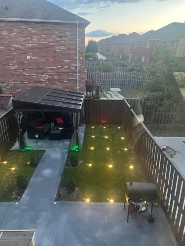 a patio with a black canopy and lights on the grass at Private room in a House in Mississauga