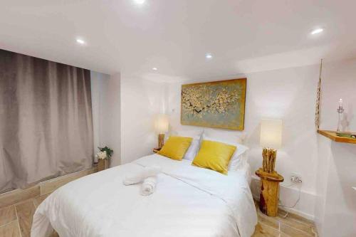 um quarto com uma grande cama branca com almofadas amarelas em Studio 1 Adorable studio neuf en bord de Marne 5kms Paris em Champigny-sur-Marne