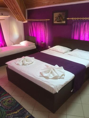 ママイアにあるLa Pasarelaの紫色の壁と紫色のカーテンが備わる客室のベッド2台