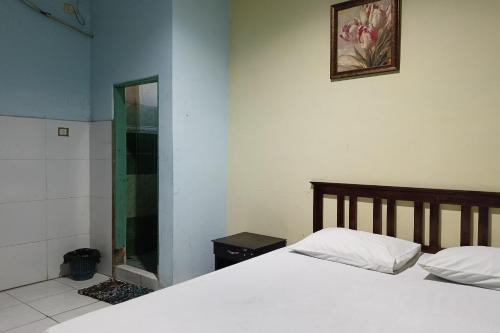 a bedroom with a white bed and a mirror at OYO 93652 Karunia Kost & Penginapan 