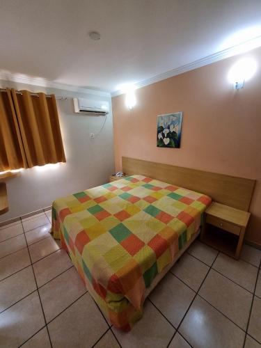 a bedroom with a bed with a colorful comforter at diRoma Fiori RM Hospedagem in Caldas Novas
