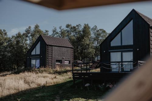 a black house with glass windows on a field at Antracytowe Domki w Górach Sowich in Sierpnica