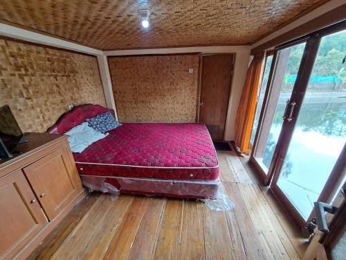 Cama roja en habitación con ventana grande en OYO 93656 Villa Cassanova Syariah, en Garut