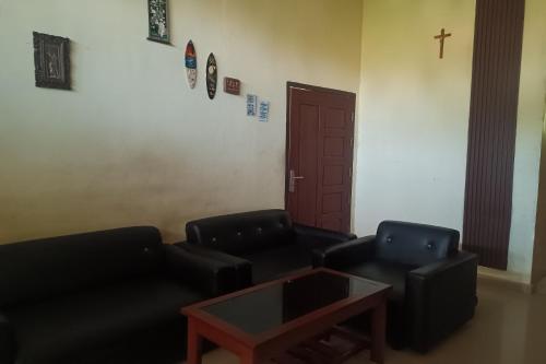 a living room with two black chairs and a table at Hotel O Homestay Purirano in Lepoleop