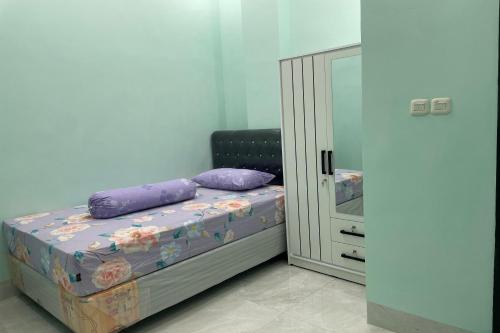 a small bed with purple pillows next to a cabinet at Hotel O Homestay Purirano in Lepoleop