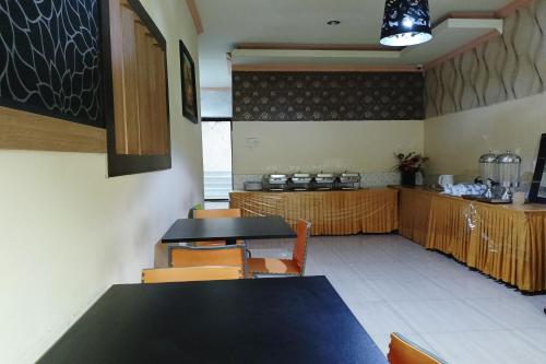 een restaurant met een tafel en stoelen en een keuken bij OYO 93665 Puri Homestay in Kendari