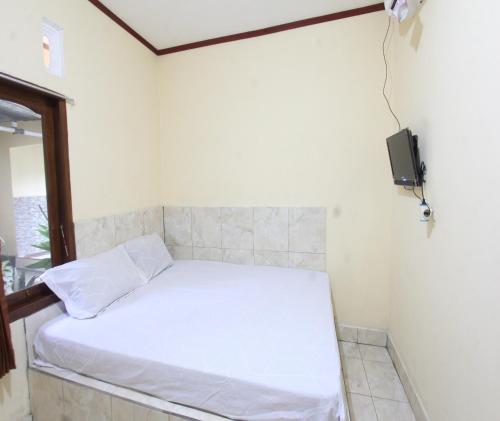 Cette chambre comprend un petit lit et une télévision murale. dans l'établissement OYO 93666 Lestari Homestay, à Lombok
