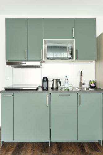 a kitchen with blue cabinets and a microwave at Marias Inn - Bed & Breakfast in Garching bei München
