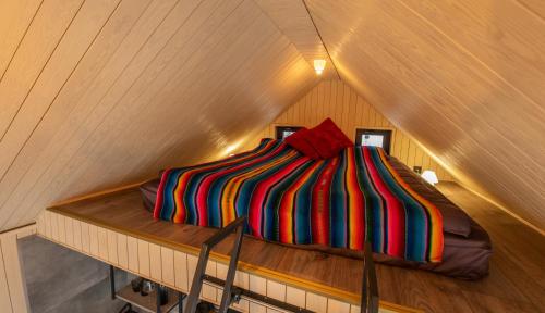 a bed with a colorful striped comforter in a attic at The Sound of Silence - romantic tiny house near Riga in Salaspils