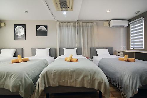 SUN House free Wifi في طوكيو: غرفة نوم مع ثلاثة أسرة مع وسائد بنية