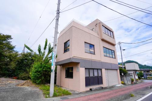 a pink building on the side of a street at 【寿家】3F建 スカイビューテラス付き！新装開店　より道の湯すぐ横 in Tsuru 