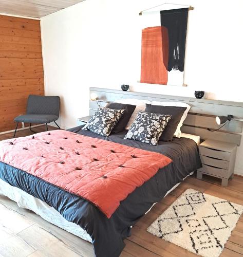 a large bed in a room with a chair at Les pieds en éventail in Lignairolles
