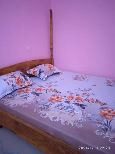 łóżko z fioletową kołdrą i 2 poduszkami w obiekcie GL GUEST HOUSE w mieście Abomey