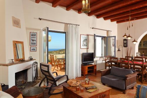 a living room with a fireplace and a dining room at Villa Spilies Kythira in Kýthira