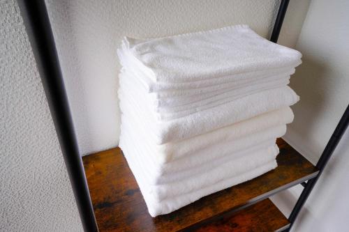 una pila de toallas blancas en un estante en 【寿家】3F建 スカイビューテラス付き！新装開店　より道の湯すぐ横 en Tsuru 