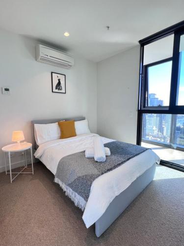 ein Schlafzimmer mit einem Bett und einem großen Fenster in der Unterkunft Heart of Melbourne CBD Skyhigh City and Sea View 2 Bedroom in Melbourne