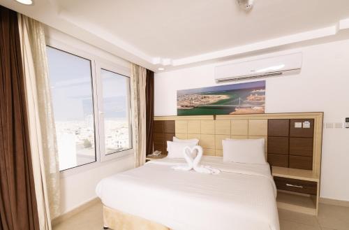 a bedroom with a large white bed with a window at Diamond Star Hotel فندق النجمة الماسية in Seeb