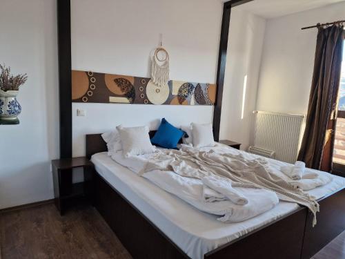 a bedroom with a large bed with white sheets at Pensiunea Hanul Dorului in Drumu Carului