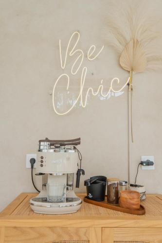 a coffee maker on a wooden table with the words he drink on the wall at Gili Boho Villas - Aesthetic Private Pool Villas in Gili Trawangan