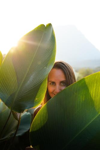 a woman is hiding behind a large green leaf at The CAMPIAN in Chiang Mai