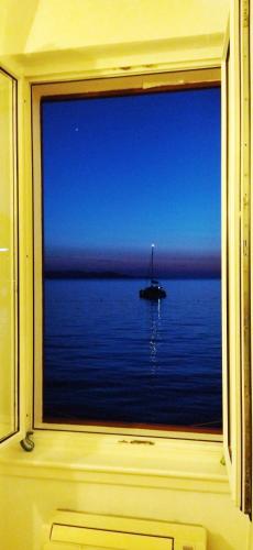 a window with a view of a boat in the water at Beach rooms Riviera - Žuta Kuća in Makarska