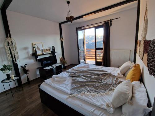 a bedroom with a large bed with a large window at Pensiunea Hanul Dorului in Drumu Carului
