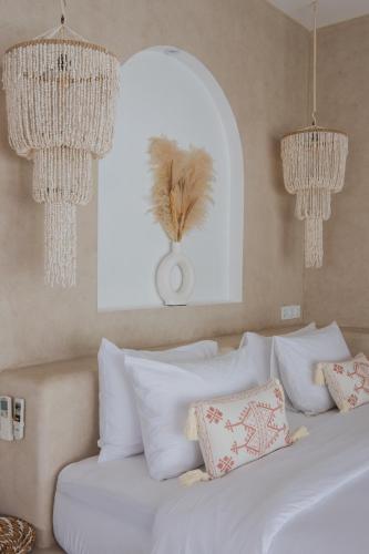 a bedroom with a bed with white pillows and chandeliers at Gili Boho Villas - Aesthetic Private Pool Villas in Gili Trawangan