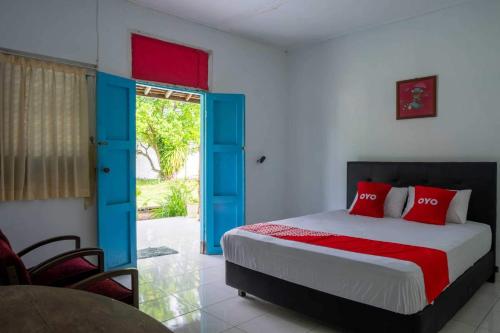 OYO 93604 Hepi Bungalow Lovina في Panji: غرفة نوم بسرير بأبواب حمراء وزرقاء