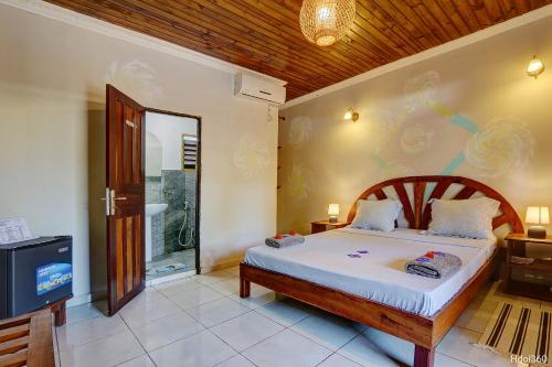 a bedroom with a bed and a tv in it at Fleurs d'Ylang in Nosy Be