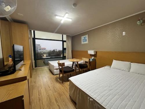 ein Hotelzimmer mit einem Bett, einem Schreibtisch und einem Tisch in der Unterkunft Seongsan Motel in Seogwipo