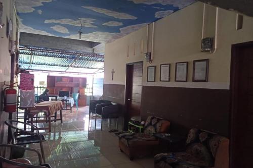 una habitación con sillas y mesas y un techo con nubes en OYO 93650 Pondok Baruga 777, en Kendari