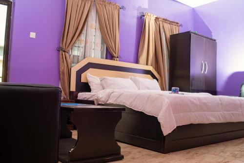 een slaapkamer met paarse muren en een groot bed bij JIKSONODO HOTEL AND SUITE in Nsukka